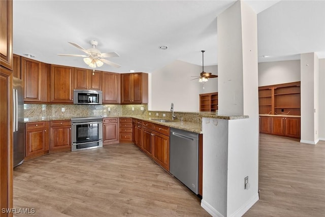 8060 Glenfinnan Cir, Fort Myers, FL 33912 - kitchen with appliances with stainless steel finishes, ceiling fan, light wood-style floors, backsplash, and brown cabinetry