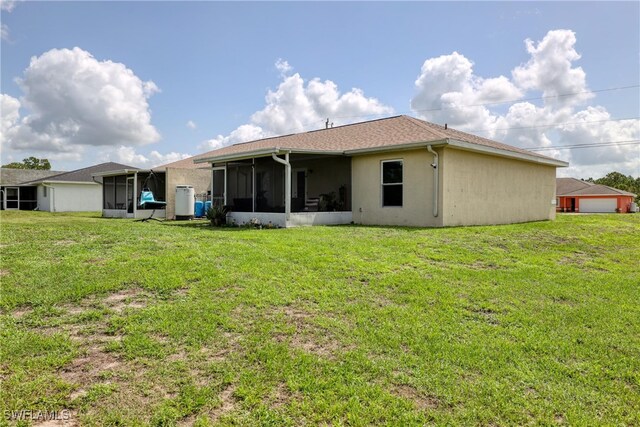 936-938 Eisenhower Blvd, Lehigh Acres, FL 33974 - rear view of house with a sunroom, a lawn, and stucco siding