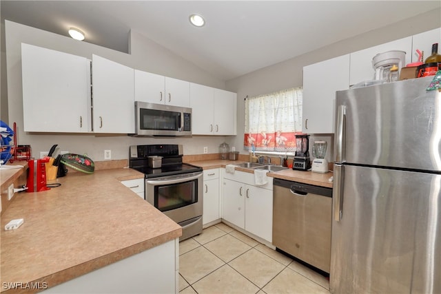 936-938 Eisenhower Blvd, Lehigh Acres, FL 33974 - kitchen featuring appliances with stainless steel finishes, lofted ceiling, light countertops, white cabinets, and light tile patterned floors