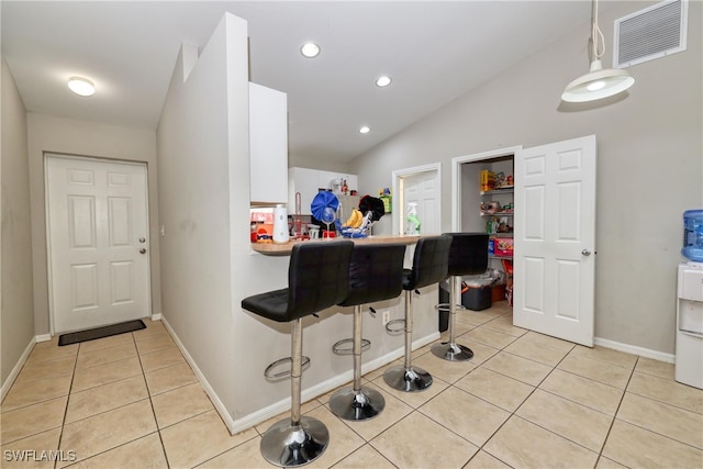 936-938 Eisenhower Blvd, Lehigh Acres, FL 33974 - kitchen with light tile patterned floors, a kitchen bar, white cabinets, lofted ceiling, and a peninsula