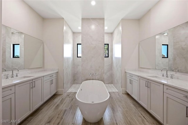 101 Beachcomber St, Marco Island, FL 34145 - full bathroom with walk in shower, a freestanding bath, two vanities, wood finished floors, and recessed lighting