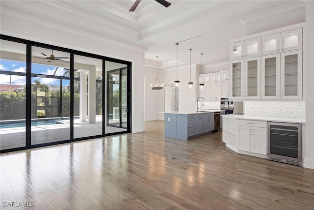 101 Beachcomber St, Marco Island, FL 34145 - kitchen featuring beverage cooler, a ceiling fan, crown molding, white cabinetry, and light countertops