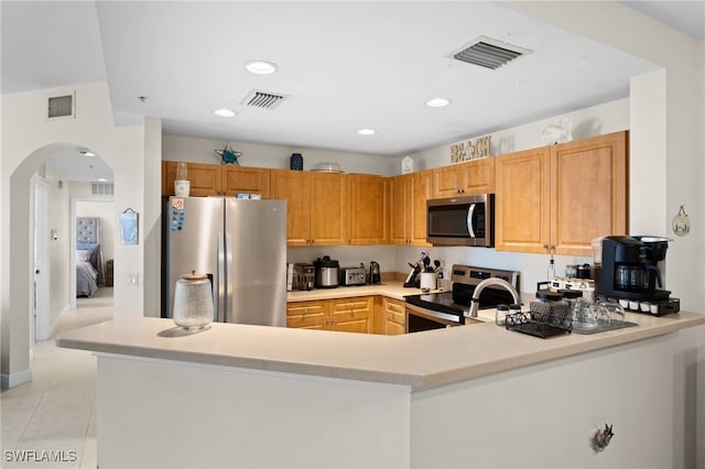 3939 Pomodoro Cir Unit 103, Cape Coral, FL 33909 - kitchen featuring appliances with stainless steel finishes, arched walkways, light countertops, a peninsula, and light tile patterned floors