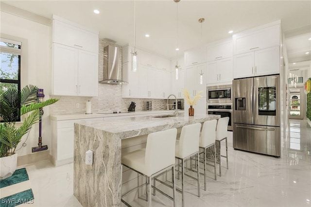 614 105th Ave N, Naples, FL 34108 - kitchen featuring stainless steel appliances, wall chimney range hood, light marble finish flooring, tasteful backsplash, and white cabinetry