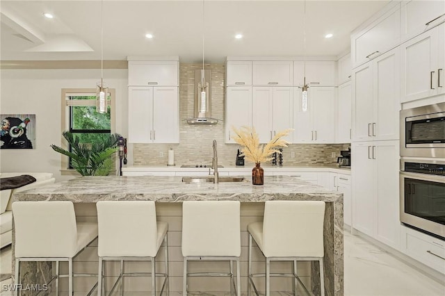 614 105th Ave N, Naples, FL 34108 - kitchen featuring appliances with stainless steel finishes, wall chimney exhaust hood, backsplash, white cabinetry, and recessed lighting