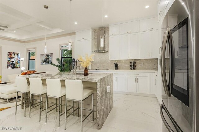 614 105th Ave N, Naples, FL 34108 - kitchen with smart refrigerator, wall chimney range hood, backsplash, light marble finish floors, and white cabinets