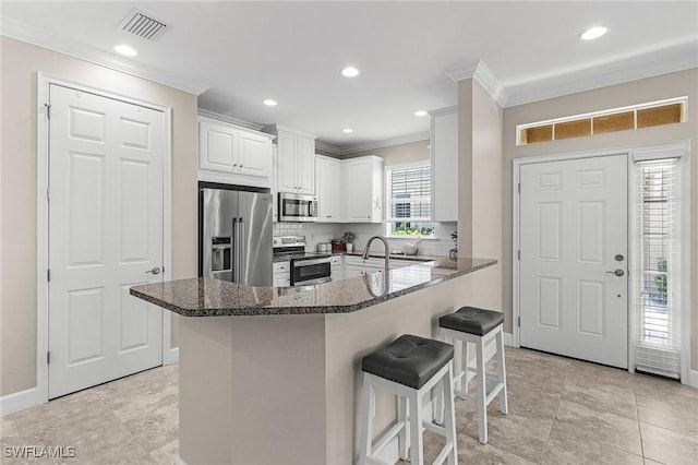 10406 Santiva Way, Fort Myers, FL 33908 - kitchen with appliances with stainless steel finishes, crown molding, a breakfast bar area, decorative backsplash, and dark stone countertops