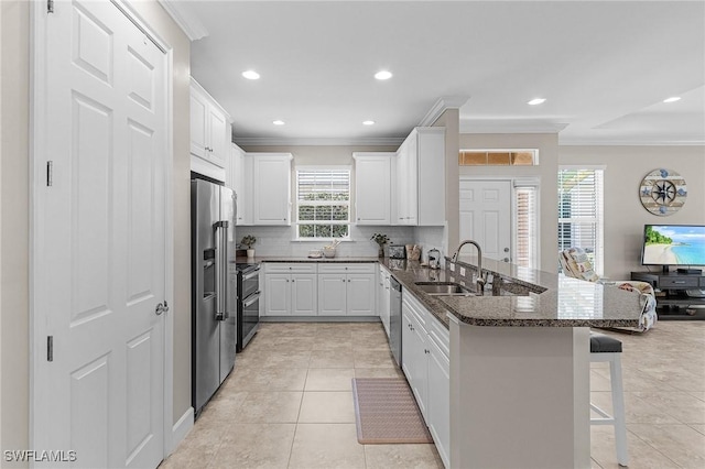 10406 Santiva Way, Fort Myers, FL 33908 - kitchen featuring a peninsula, a kitchen bar, appliances with stainless steel finishes, ornamental molding, and backsplash