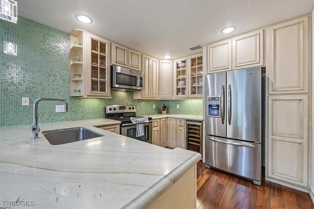 60 Emerald Woods Dr Unit B11, Naples, FL 34108 - kitchen with appliances with stainless steel finishes, beverage cooler, dark wood-style flooring, cream cabinetry, and light stone countertops
