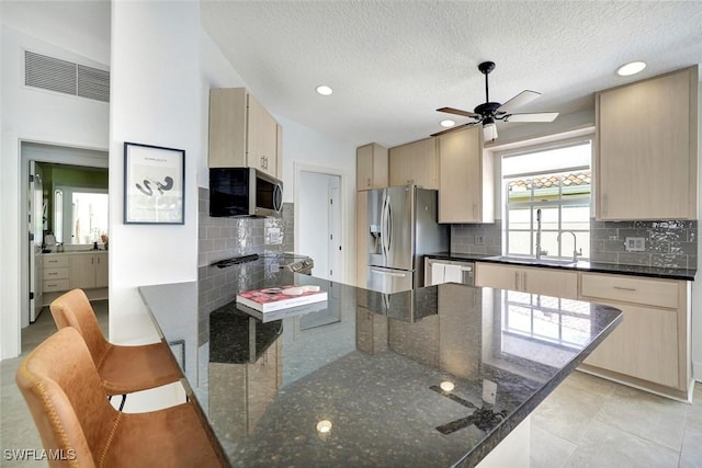 3128 Andorra Ct, Naples, FL 34109 - kitchen featuring appliances with stainless steel finishes, a ceiling fan, a breakfast bar area, a textured ceiling, and decorative backsplash