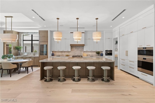 850 10th St N, Naples, FL 34102 - kitchen with modern cabinets, tasteful backsplash, a kitchen bar, white cabinetry, and recessed lighting
