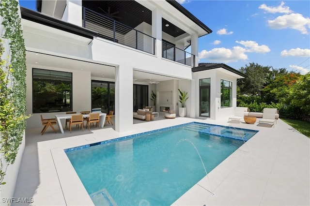 850 10th St N, Naples, FL 34102 - rear view of property with a balcony, outdoor lounge area, a patio, stucco siding, and a pool with connected hot tub