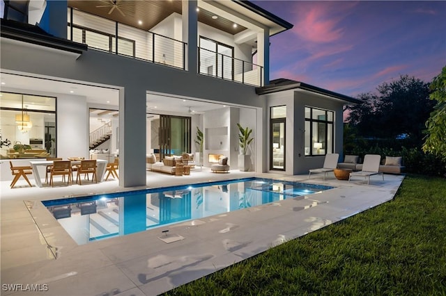 850 10th St N, Naples, FL 34102 - back of property at dusk featuring a balcony, an outdoor living space, a patio, ceiling fan, and stucco siding