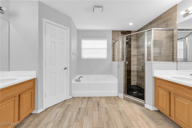 8094 Silver Birch Way, Lehigh Acres, FL 33971 - bathroom with two vanities, a stall shower, a bath, and wood finished floors