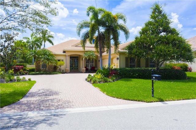 3681 Mossy Oak Dr, Fort Myers, FL 33905 - view of front of home with curved driveway, a front yard, a tiled roof, and french doors