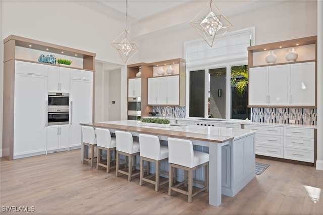 4297 Deephaven Ln, Naples, FL 34119 - kitchen featuring open shelves, white cabinets, light countertops, and decorative backsplash