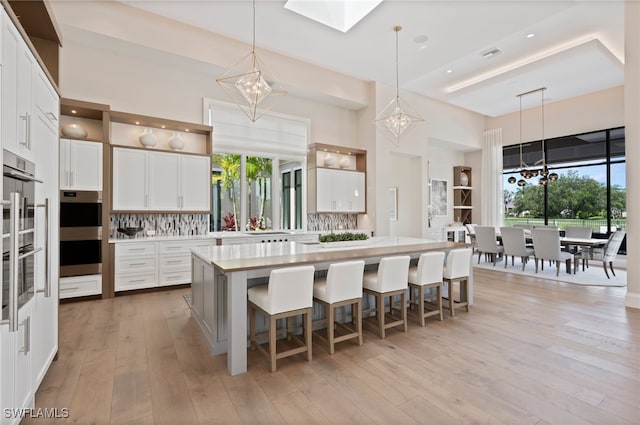 4297 Deephaven Ln, Naples, FL 34119 - kitchen featuring a chandelier, light countertops, backsplash, white cabinetry, and a high ceiling