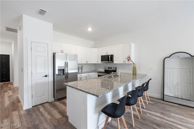 2429/2431 Lola Ave S, Lehigh Acres, FL 33973 - kitchen with stainless steel appliances, a peninsula, a kitchen breakfast bar, white cabinets, and light stone counters