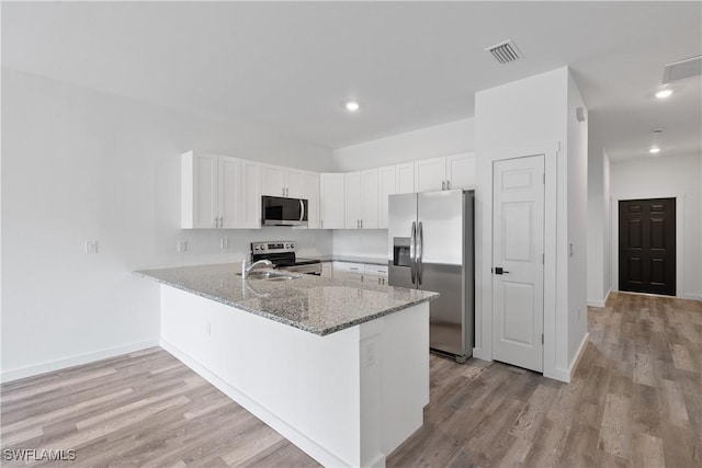 2429/2431 Lola Ave S, Lehigh Acres, FL 33973 - kitchen with stainless steel appliances, a peninsula, white cabinetry, light stone countertops, and light wood-style floors