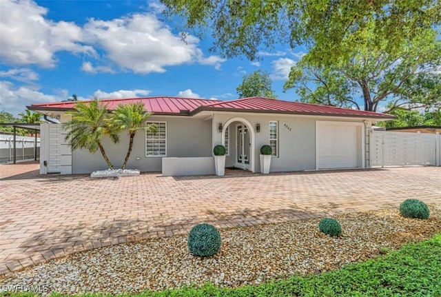 4442 18th Ave SW, Naples, FL 34116 - view of front facade with stucco siding, a garage, a standing seam roof, a metal roof, and driveway