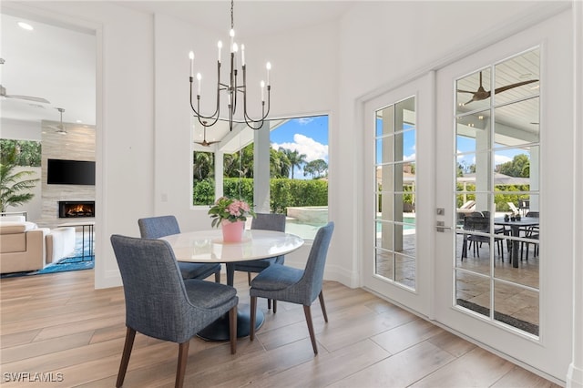 2274 Hawksridge Dr, Naples, FL 34105 - dining area featuring light wood finished floors, a premium fireplace, a chandelier, and a high ceiling