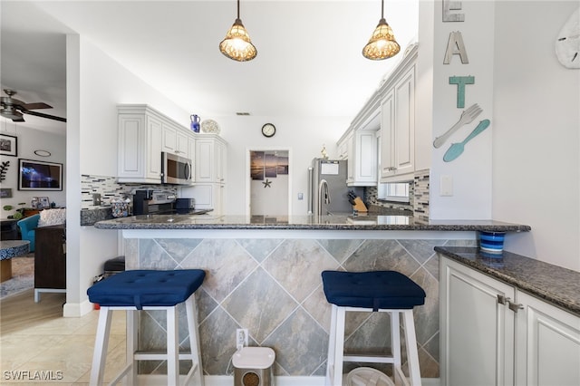 15050 Lakeside View Dr Unit 1001, Fort Myers, FL 33919 - kitchen featuring appliances with stainless steel finishes, a kitchen breakfast bar, dark stone counters, ceiling fan, and tasteful backsplash