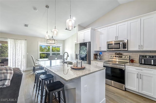 2806 22nd St W, Lehigh Acres, FL 33971 - kitchen with appliances with stainless steel finishes, backsplash, light wood finished floors, lofted ceiling, and plenty of natural light