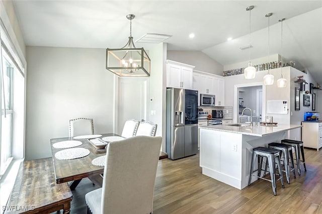 2806 22nd St W, Lehigh Acres, FL 33971 - kitchen featuring appliances with stainless steel finishes, lofted ceiling, a chandelier, white cabinetry, and wood finished floors