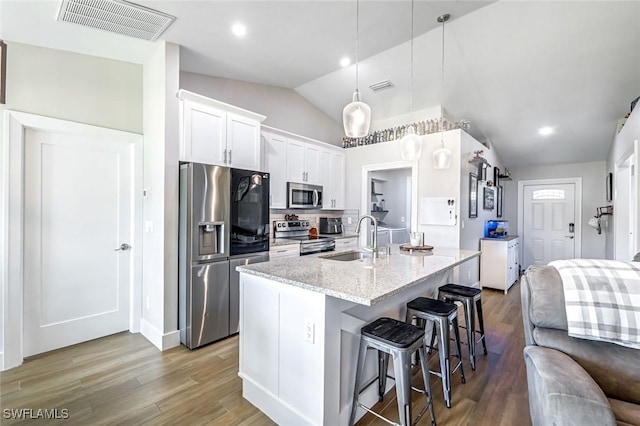 2806 22nd St W, Lehigh Acres, FL 33971 - kitchen with stainless steel appliances, vaulted ceiling, a breakfast bar, light wood finished floors, and an island with sink