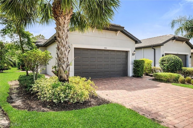 7690 Jacaranda Ln, Naples, FL 34114 - view of front of property with a garage, decorative driveway, stucco siding, a tiled roof, and a front yard