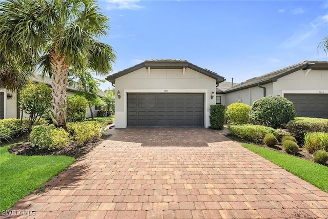 7690 Jacaranda Ln, Naples, FL 34114 - ranch-style home with decorative driveway, a garage, and stucco siding