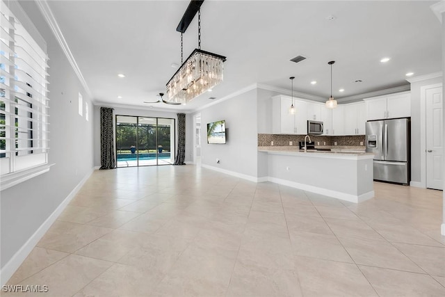 7690 Jacaranda Ln, Naples, FL 34114 - kitchen with stainless steel appliances, crown molding, open floor plan, decorative backsplash, and light countertops