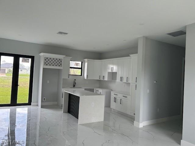 2603 3rd St SW, Lehigh Acres, FL 33976 - kitchen featuring light marble finish floors, a center island, and white cabinets
