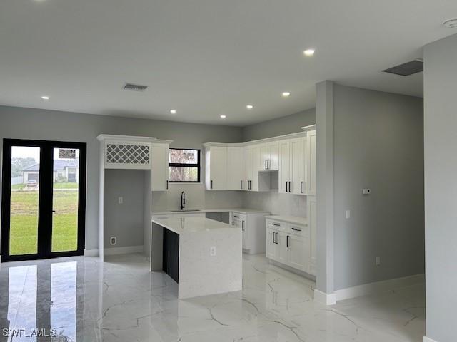 2603 3rd St SW, Lehigh Acres, FL 33976 - kitchen featuring light marble finish flooring, a kitchen island, recessed lighting, and white cabinets