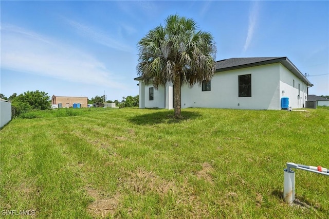 472 Rajah St, Lehigh Acres, FL 33974 - back of property with stucco siding and a yard