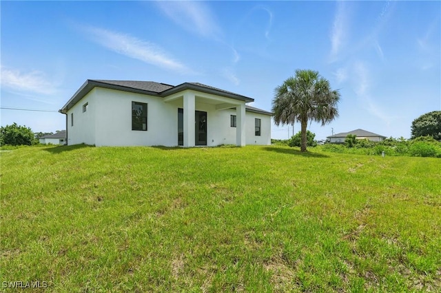 472 Rajah St, Lehigh Acres, FL 33974 - rear view of property with stucco siding and a lawn