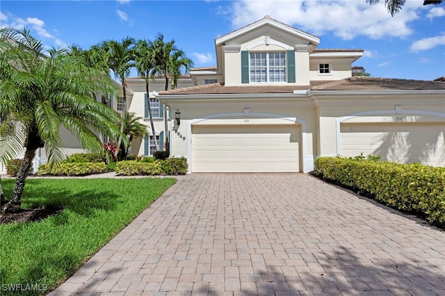 28649 San Lucas Ln Unit 102, Bonita Springs, FL 34135 - view of front of house featuring decorative driveway, stucco siding, a garage, a front lawn, and a tiled roof