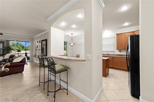 28649 San Lucas Ln Unit 102, Bonita Springs, FL 34135 - kitchen featuring freestanding refrigerator, open floor plan, crown molding, light tile patterned floors, and brown cabinetry