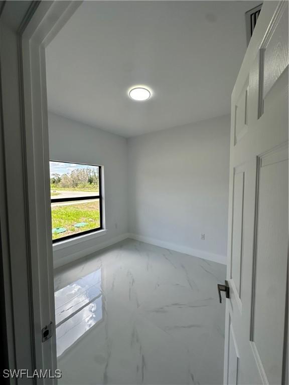 821 Bell Blvd S, Lehigh Acres, FL 33974 - spare room featuring marble look tiles and baseboards