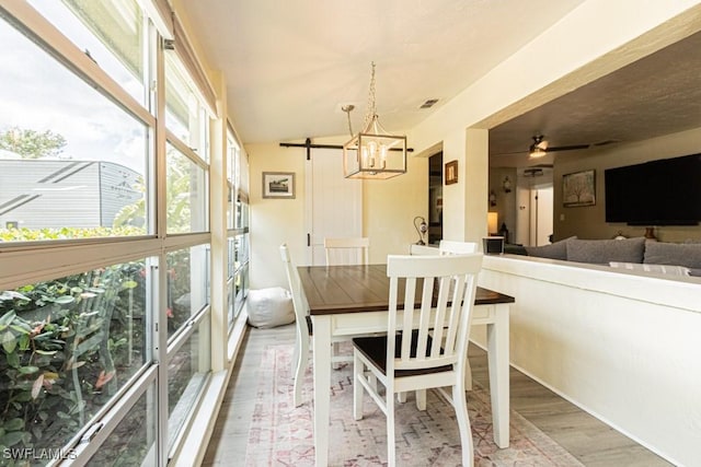 1413 Davis Dr, Fort Myers, FL 33919 - dining space with wood finished floors, a chandelier, a ceiling fan, and a barn door