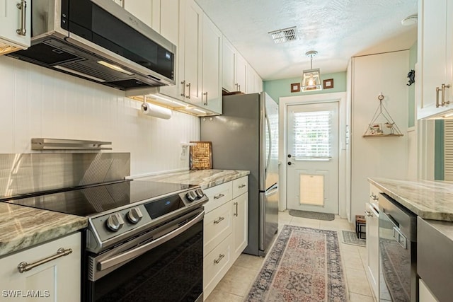 1413 Davis Dr, Fort Myers, FL 33919 - kitchen featuring appliances with stainless steel finishes, white cabinetry, light stone countertops, light tile patterned floors, and pendant lighting