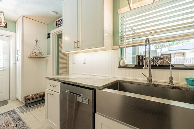 1413 Davis Dr, Fort Myers, FL 33919 - kitchen with stainless steel dishwasher, light stone counters, plenty of natural light, and light tile patterned floors