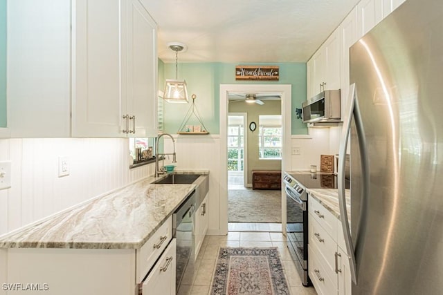 1413 Davis Dr, Fort Myers, FL 33919 - kitchen featuring stainless steel appliances, light tile patterned floors, white cabinets, ceiling fan, and a wainscoted wall