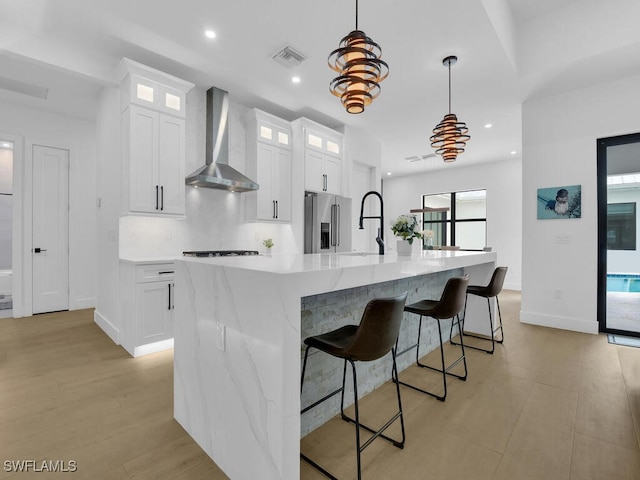 3475 3rd Ave SW, Naples, FL 34117 - kitchen with wall chimney range hood, appliances with stainless steel finishes, a large island, white cabinets, and light countertops