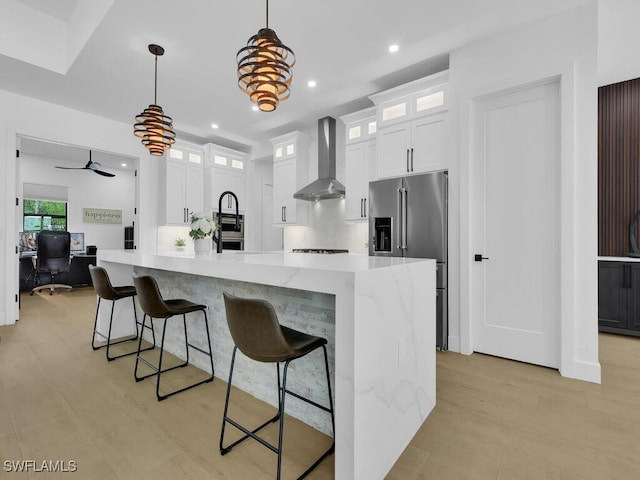 3475 3rd Ave SW, Naples, FL 34117 - kitchen with wall chimney exhaust hood, high end refrigerator, a desk, white cabinets, and recessed lighting
