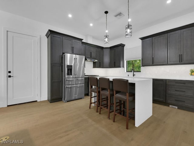 3475 3rd Ave SW, Naples, FL 34117 - kitchen featuring high end refrigerator, under cabinet range hood, light countertops, a kitchen island, and light wood-style flooring