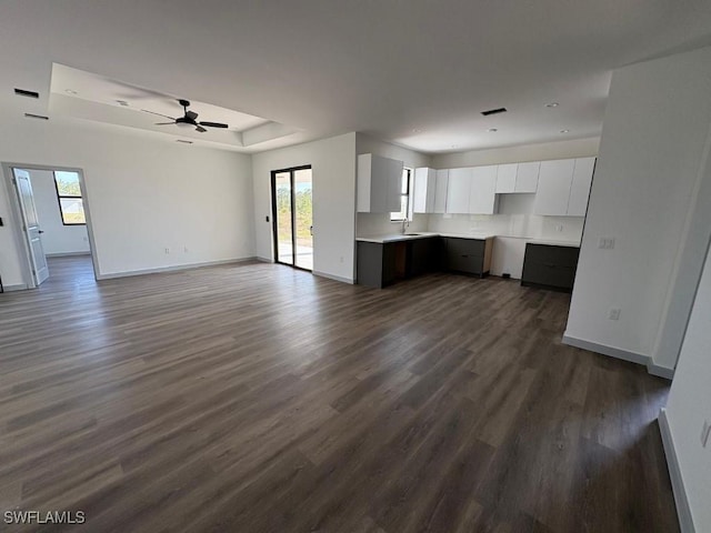 1024 Halby Ave S, Lehigh Acres, FL 33974 - unfurnished living room with a tray ceiling, dark wood-style floors, and a ceiling fan