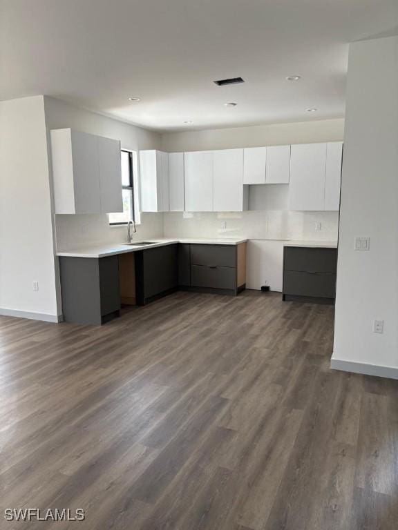 1024 Halby Ave S, Lehigh Acres, FL 33974 - kitchen with modern cabinets, white cabinets, dark wood-style flooring, and light countertops