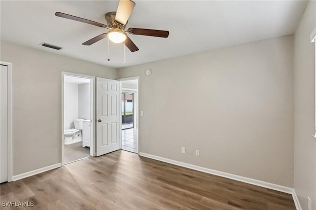 740 SW 5th St, Cape Coral, FL 33991 - unfurnished bedroom featuring wood finished floors, connected bathroom, and ceiling fan