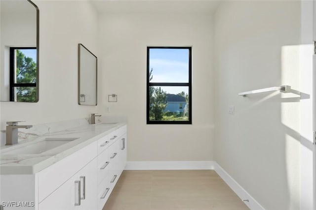 3115 41st St SW, Lehigh Acres, FL 33976 - full bath with healthy amount of natural light, double vanity, and wood finished floors